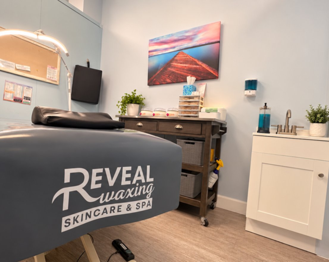 Reveal Waxing treatment room with branded wax bed, sink and supply cart