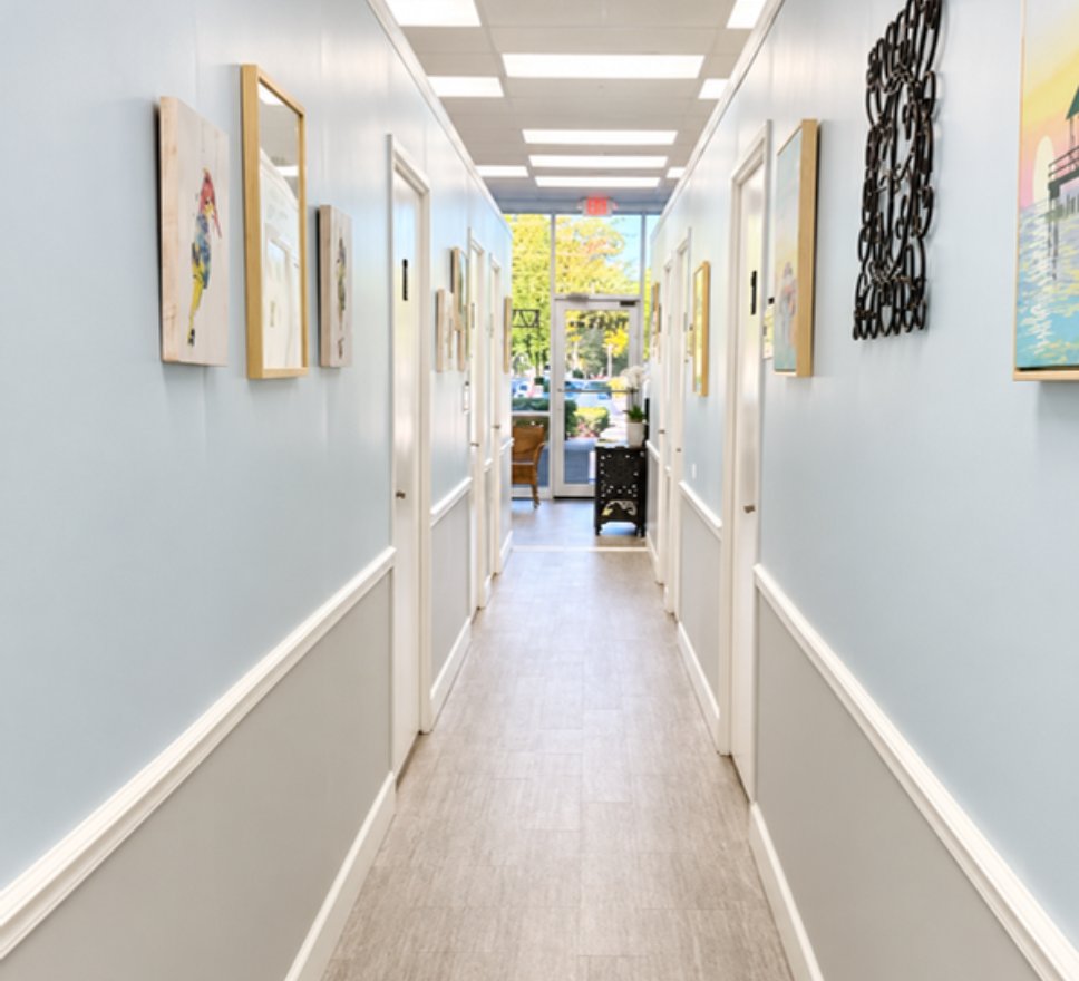 Hallway of treatment rooms at Reveal with framed art and natural light